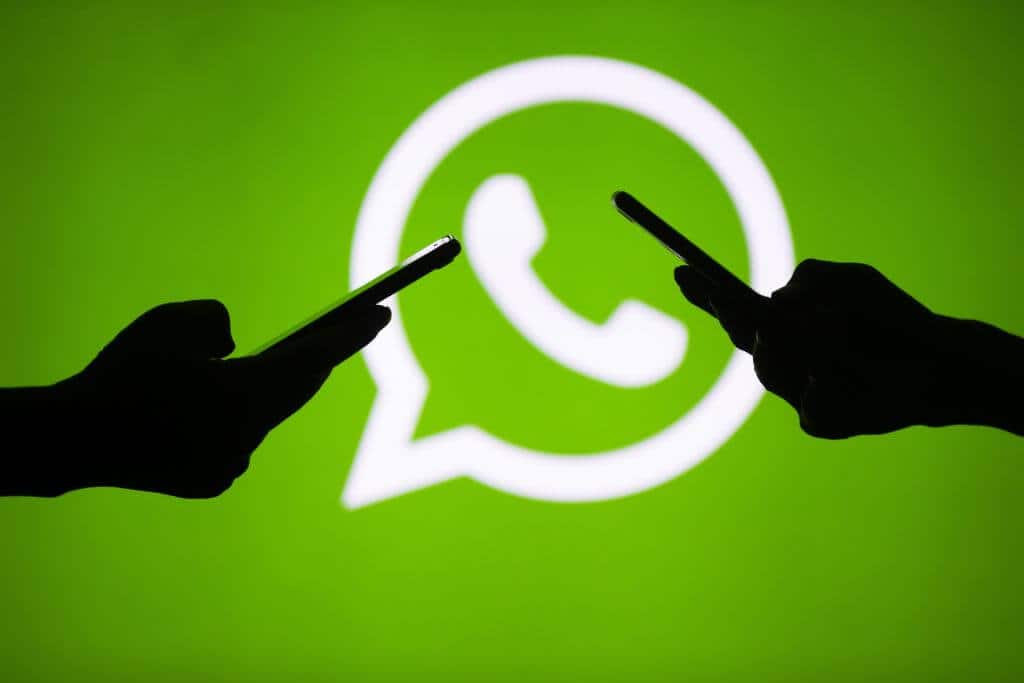 Dłonie z telefonami na tle logo WhatsApp