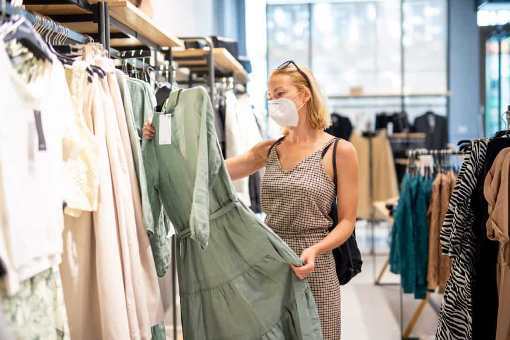 Kobieta w maseczce robiąca zakupy w sklepie odzieżowym